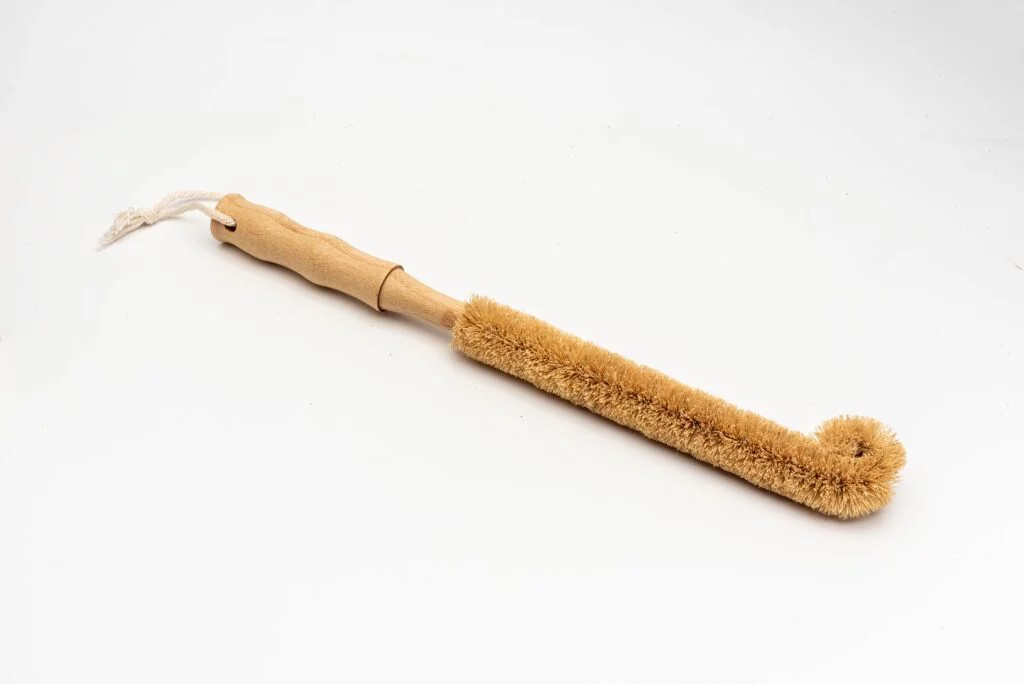 Escova para garrafas com cabo de bambu, cordão de algodão e cerdas de sisal.