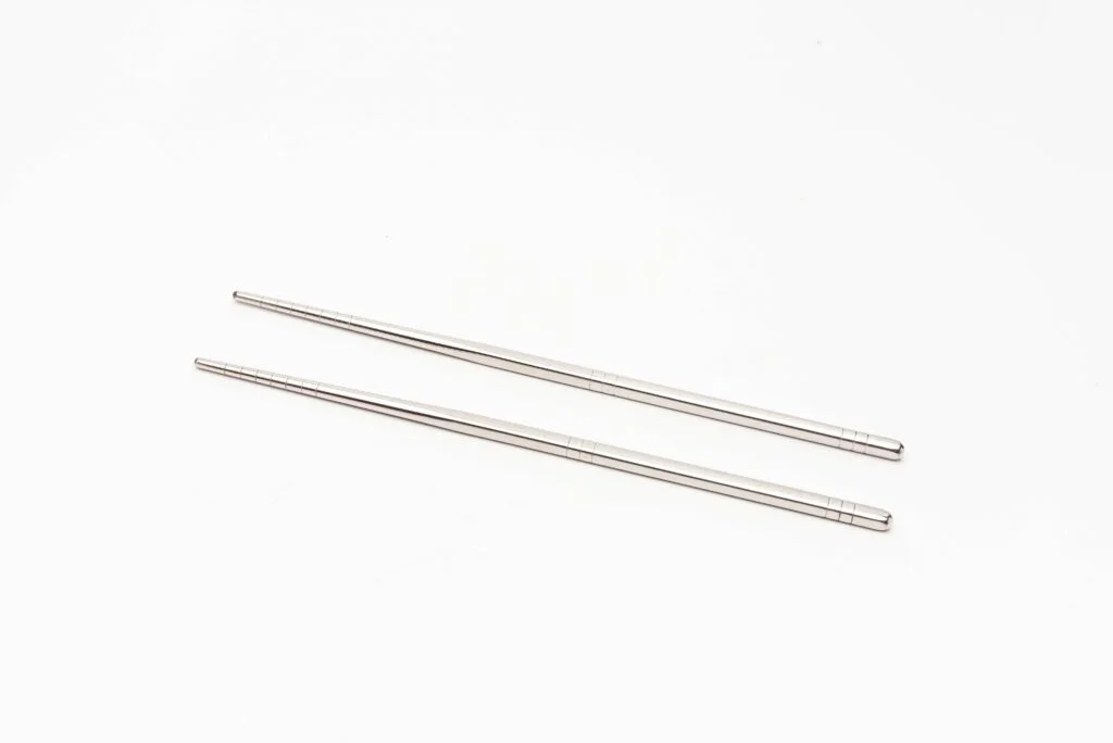 Imagem de pauzinhos quadrados de aço inoxidável com um design hexagonal exclusivo para maior aderência e estabilidade. Esses pauzinhos de metal antiderrapantes são duráveis e elegantes, garantindo uma experiência gastronômica segura.