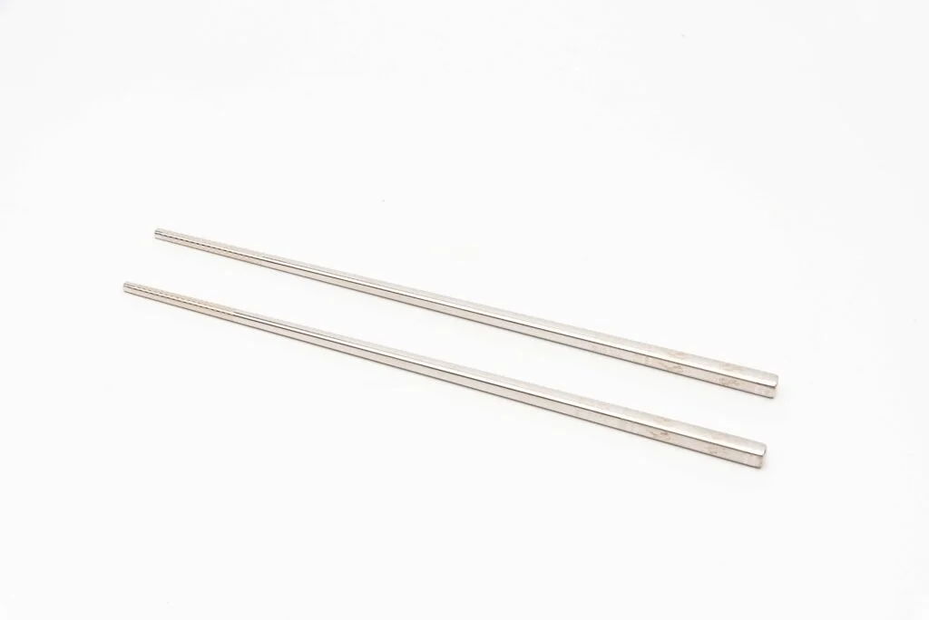 A imagem "Chopsticks de metal com design de peixe e material 304" seria: "Pauzinhos de metal com desenho de peixe nadando, feitos de aço inoxidável 304.
