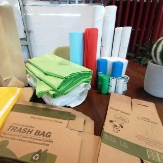 An assortment of compostable bags, including biodegradable garbage bags, shipping envelopes, tote bags, pet waste bags, kitchen compost bags, and shopping bags. These eco-friendly bags are designed to break down naturally, reducing environmental impact.